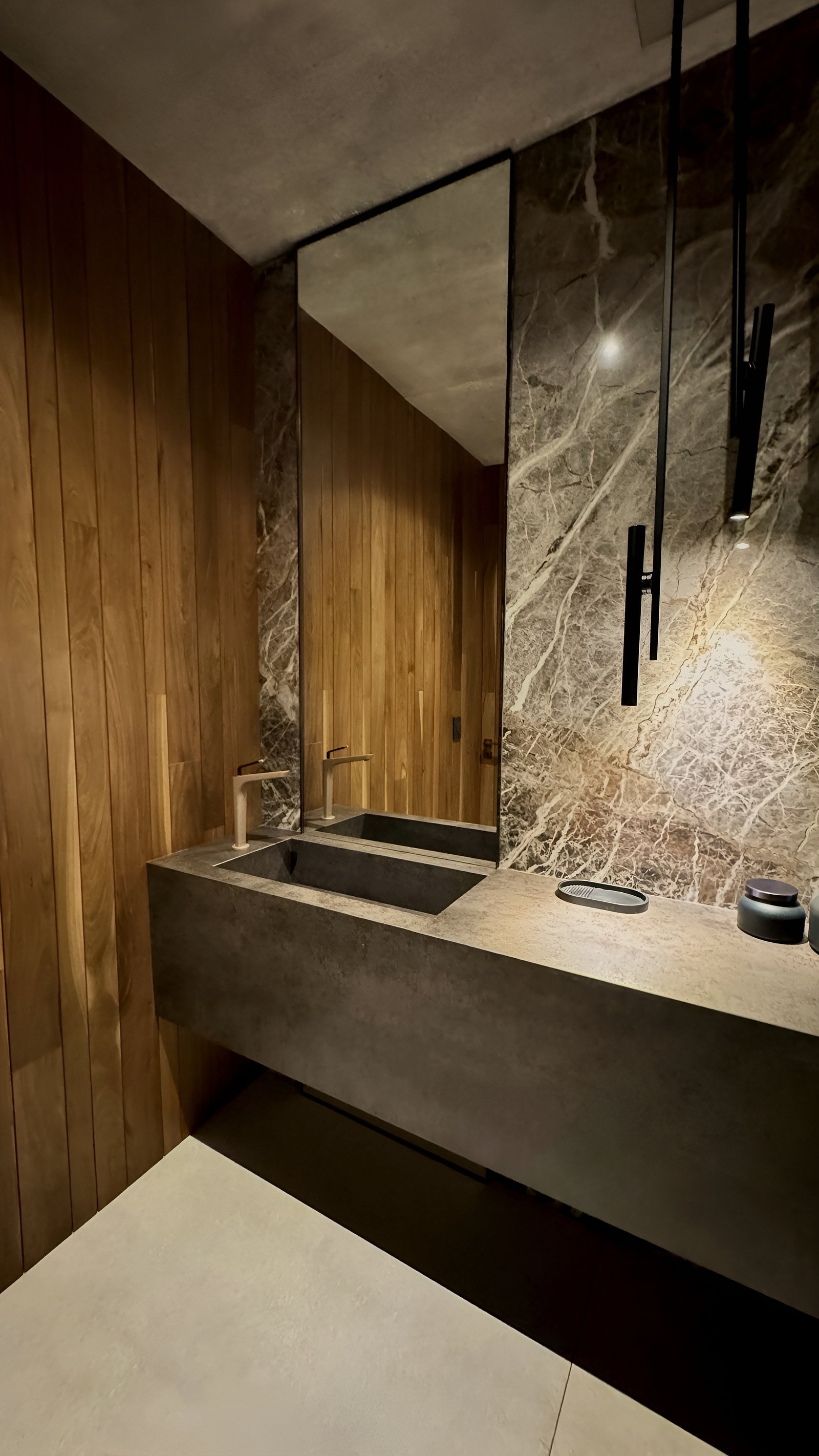 Banheiro moderno com parede de madeira, pia integrada e detalhes dourados — projeto CASA MHN, por Hermann Arquitectos, em Nordelta